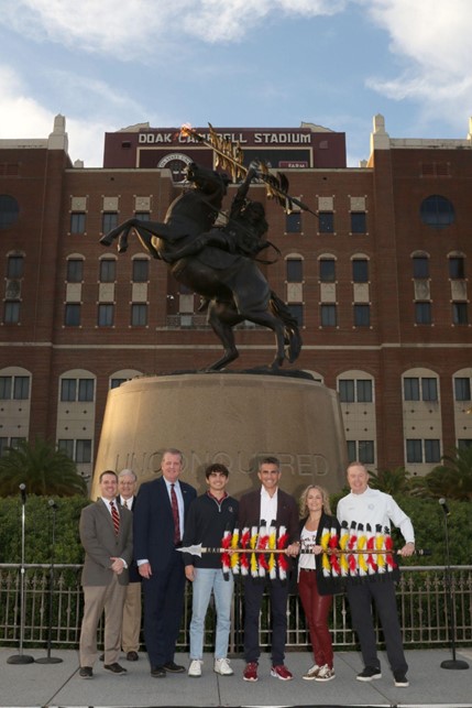  Seminole Boosters members holding FSU spear in front of Doak Campbell Stadium